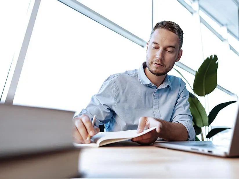 male accountant sitting at desk writing notes.jpg